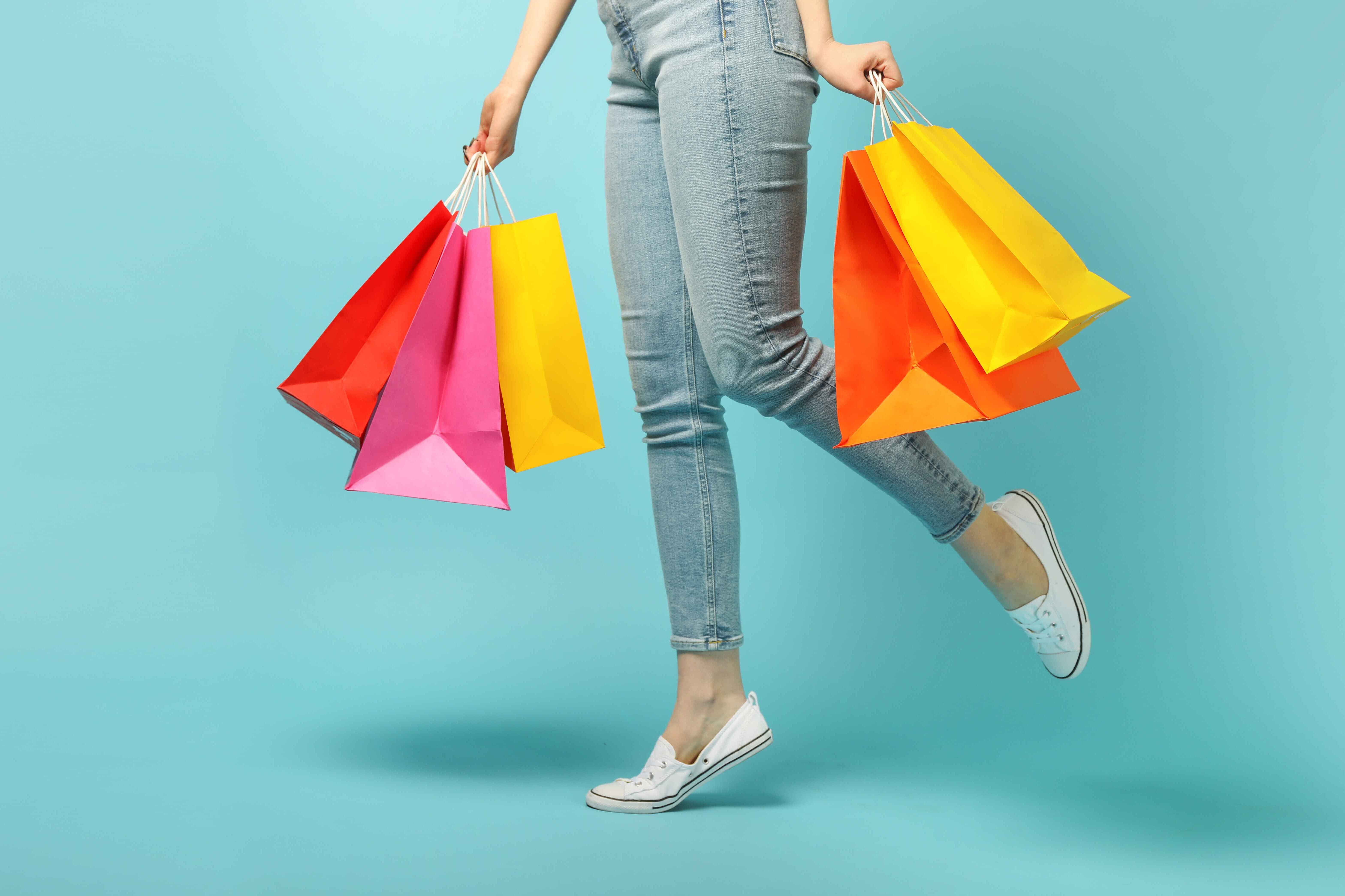 Eine Person hält in beiden Händen Einkaufstaschen.