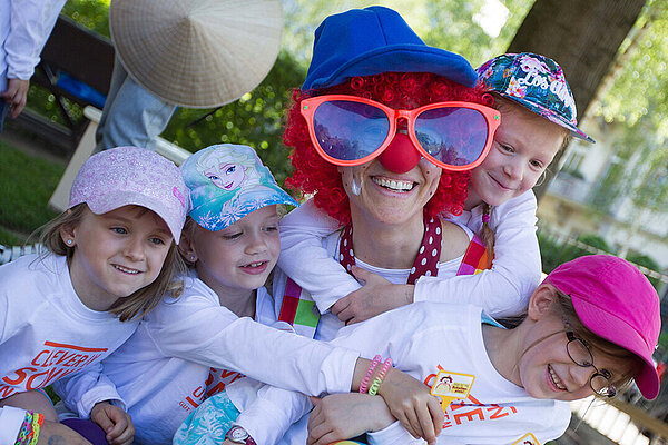 Ein Clown albert mit vier kleinen Kindern.